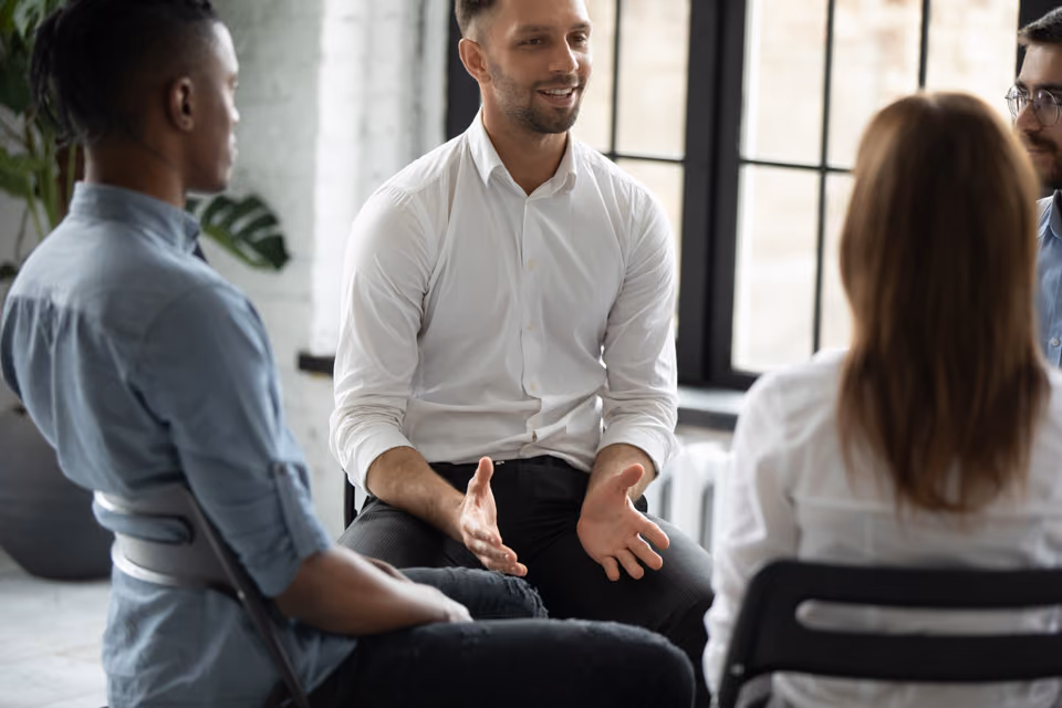 Trainer im Gespräch mit einer kleinen Seminargruppe in einem hellen Raum